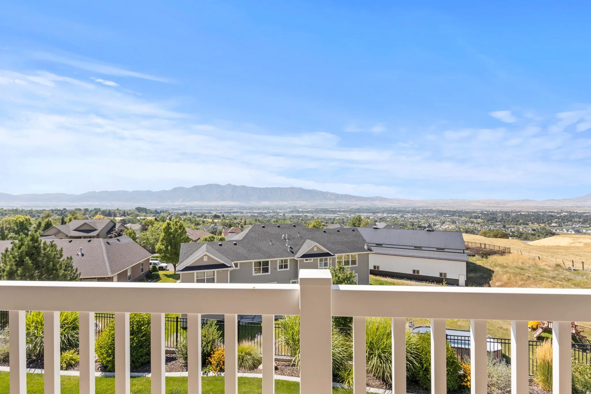 Expansive mountain and city scenery from a private balcony with white railings