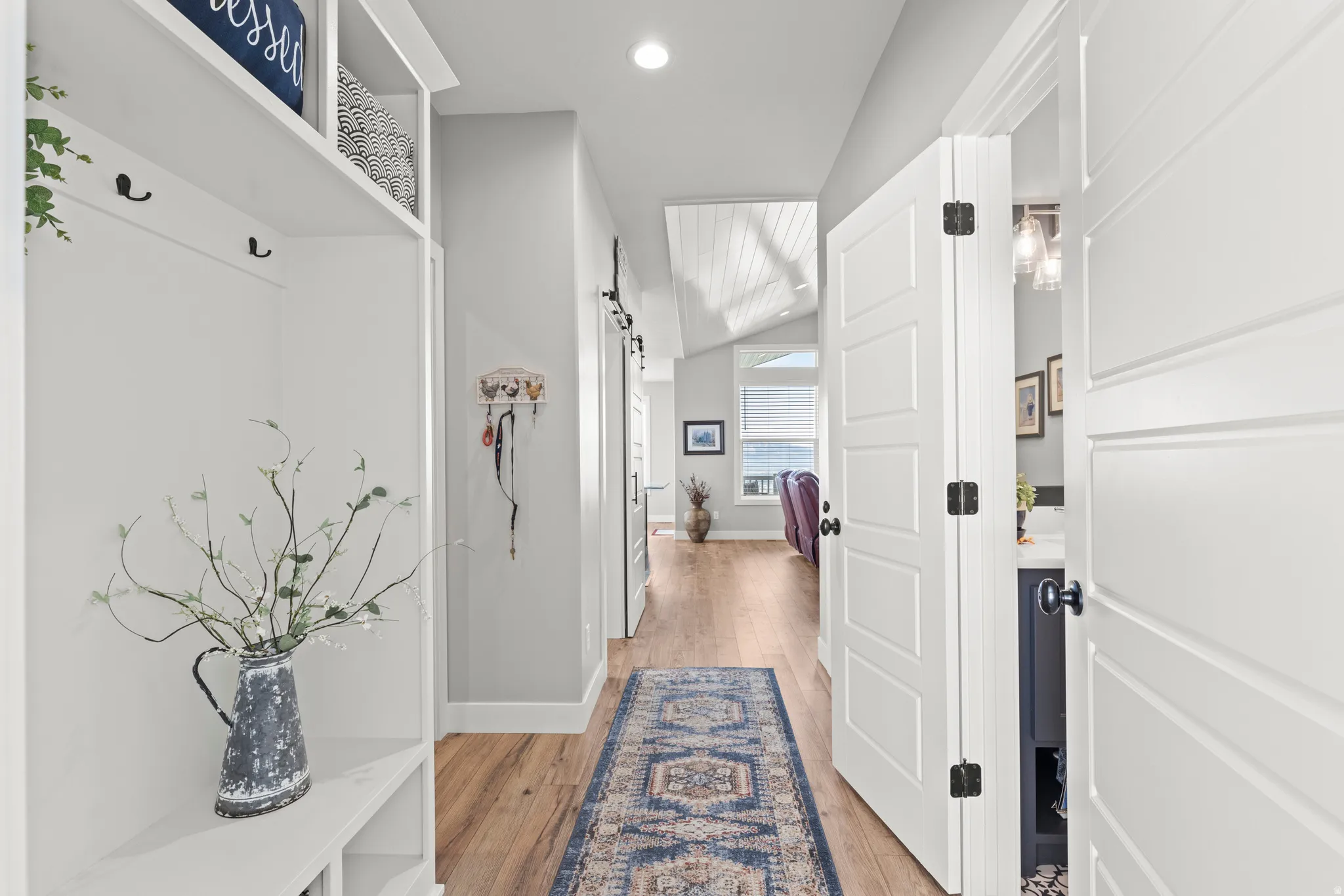 Hallway featuring wood-finish flooring, recessed lighting, and a white built-in storage unit with hooks and shelving