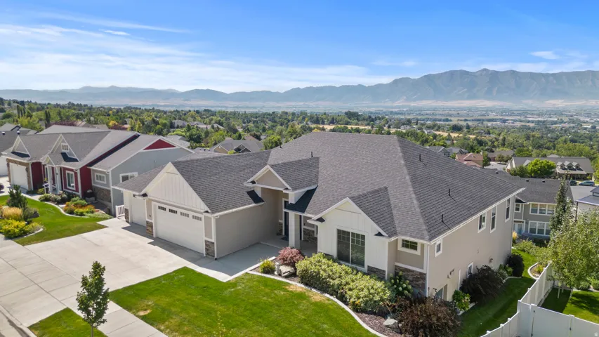 Contemporary residence featuring a two-car garage, stone accents, and a landscaped front yard with established plantings