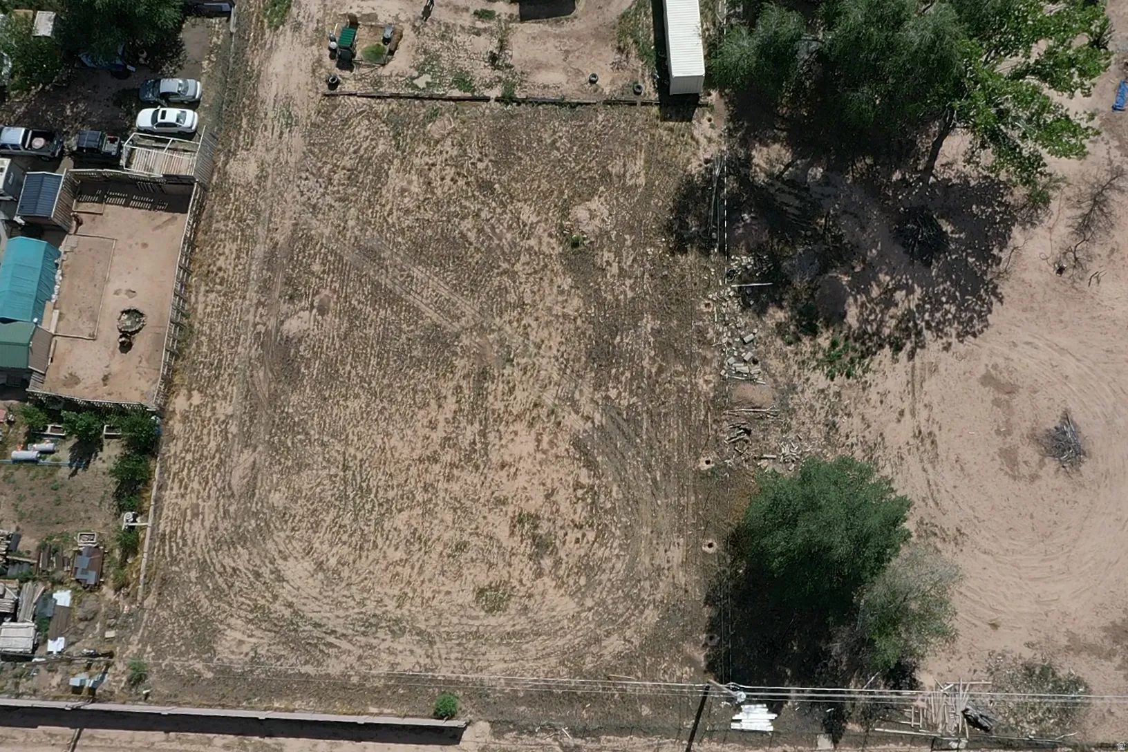 Expansive lot with varied terrain, featuring several mature trees and perimeter fencing