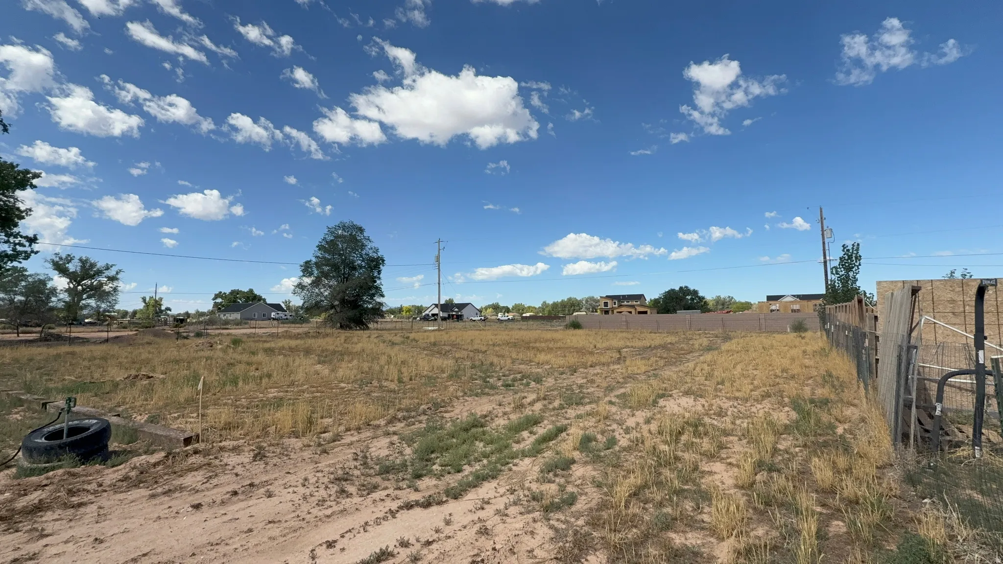Expansive land parcel featuring natural ground cover and distant residential structures