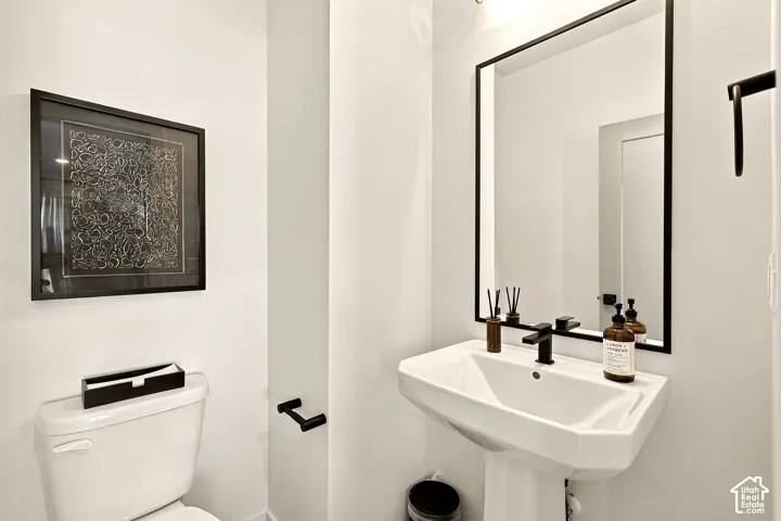 Pedestal sink with a matte black single-handle faucet, rectangular mirror with a matching black frame, and coordinated matte black wall-mounted hardware