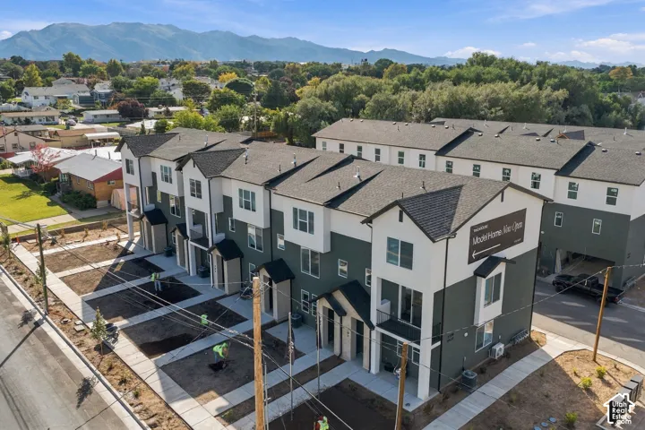 Multi-story townhome complex featuring two-tone exterior cladding, gable rooflines, private covered balconies, and mountain scenery