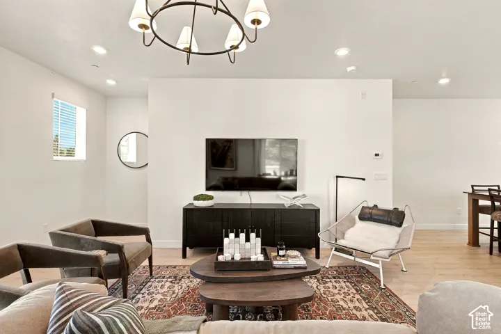 Open-concept living space featuring wood-finish flooring, recessed lighting, and a modern tiered chandelier