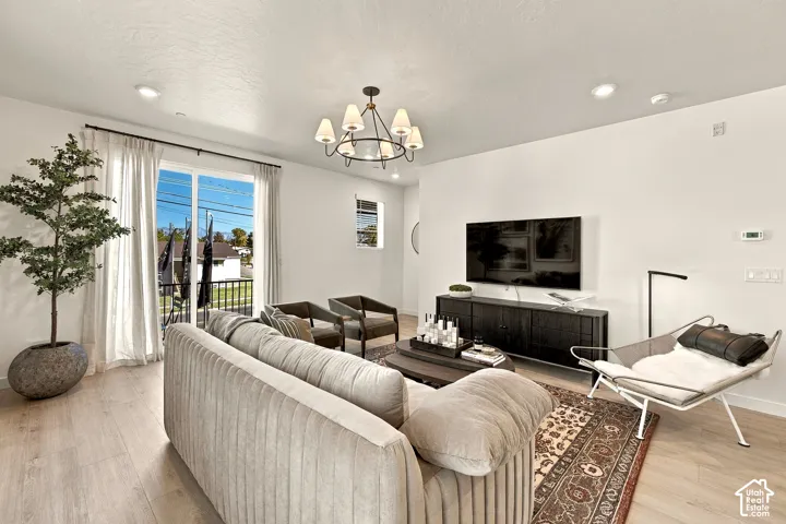 Living area featuring wood-finish flooring, recessed lighting, a multi-arm chandelier, and sliding glass doors