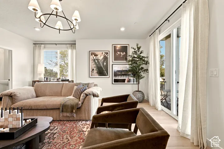 Living area featuring light-toned wood-finish flooring, a multi-arm modern chandelier, sliding glass doors, and dual-pane windows