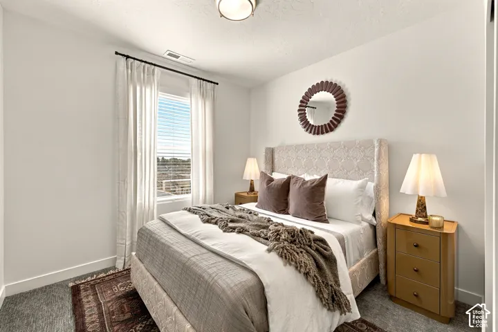 Bedroom with carpeted flooring, neutral wall tones, and a window with a rod-mounted curtain set