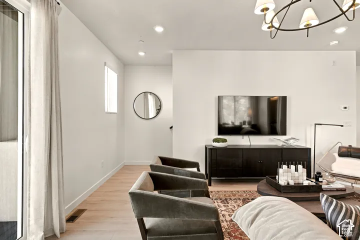 Living area featuring wood-finish flooring, recessed lighting, a modern multi-arm chandelier, and glass sliding door access