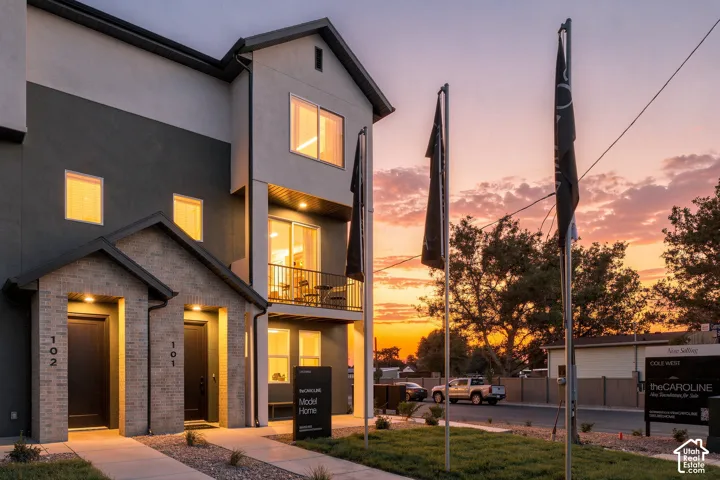 Multi-level exterior featuring a combination of brick masonry and smooth-finish siding, a second-story balcony with metal railing, and recessed entryway lighting