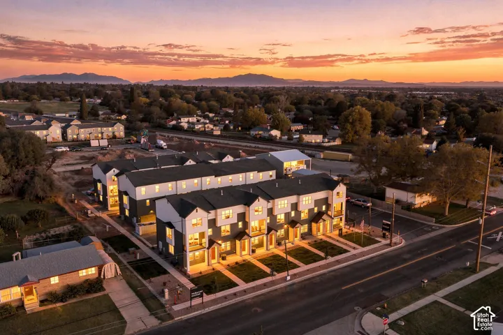 Multi-unit residential complex featuring multi-story contemporary architecture, high-contrast exterior siding, gabled rooflines, and manicured lawn frontage