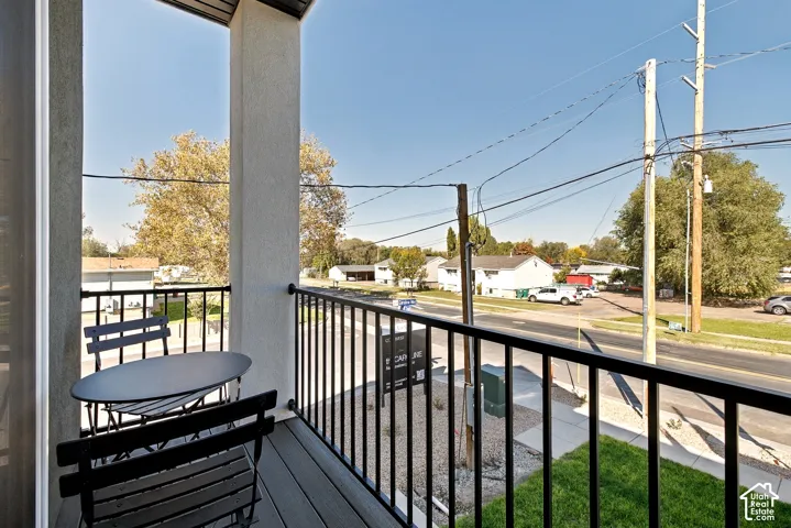 Covered balcony featuring composite decking and a black metal railing