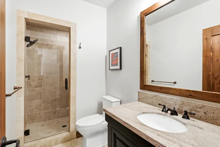 Walk-in shower with clear glass enclosure and stone-tiled surround