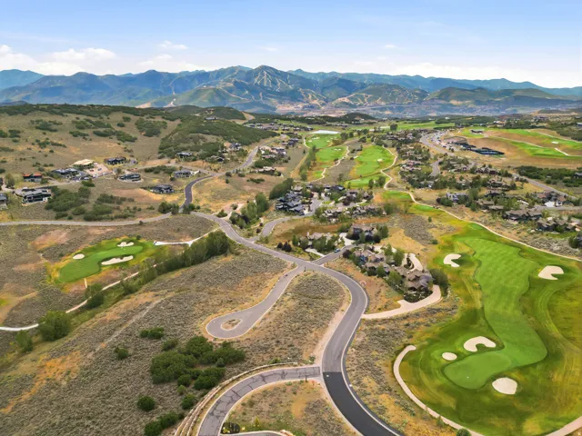 Expansive mountain terrain featuring a golf course, paved roadways, and residential properties