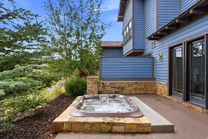 Outdoor hot tub set within a stone surround, complemented by a composite decking accent