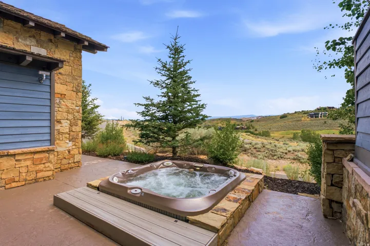 Outdoor spa with integrated steps, surrounded by stacked stone and a concrete patio