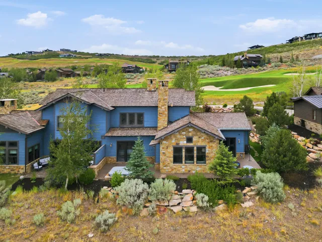 Contemporary residence featuring blue siding and stone accents, a multi-level roofline, and an integrated outdoor patio with a hot tub
