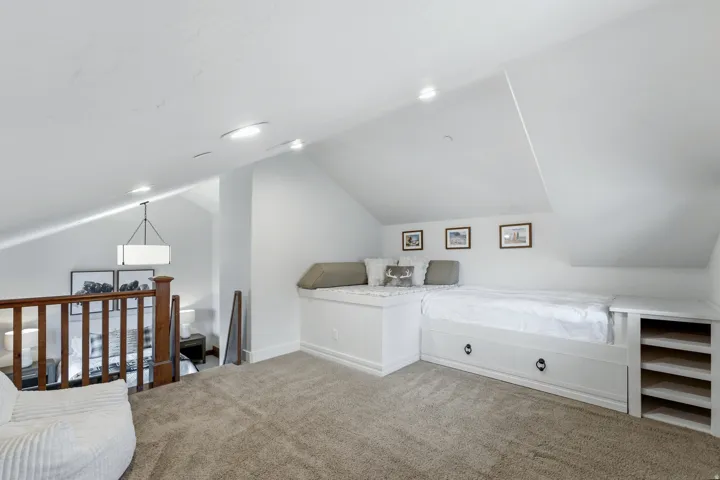 Carpeted loft area featuring a built-in bed with storage drawers, integrated shelving, and a built-in window seat