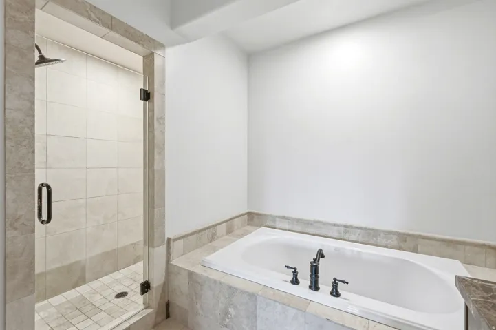 Built-in soaking tub with matte black fixtures, framed by a tiled deck