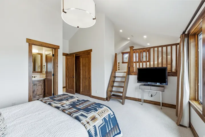Spacious room featuring vaulted ceilings, wood-finish trim, a carpeted floor, an integrated loft with wood railing, and a built-in ladder