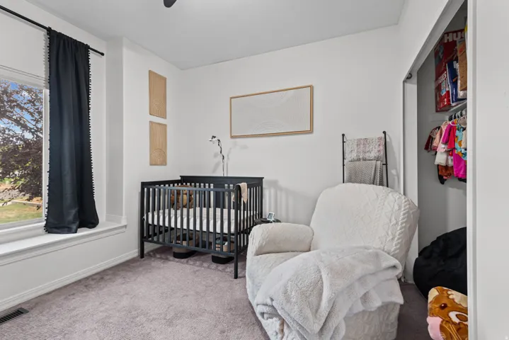 Carpeted room featuring a large window with white trim, a built-in closet with shelving, and white painted walls