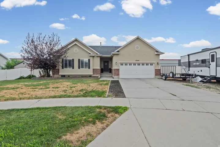 Rambler-style residence featuring a combination facade of stucco and brick accents, a two-car garage, and a concrete driveway and huge RV pad.