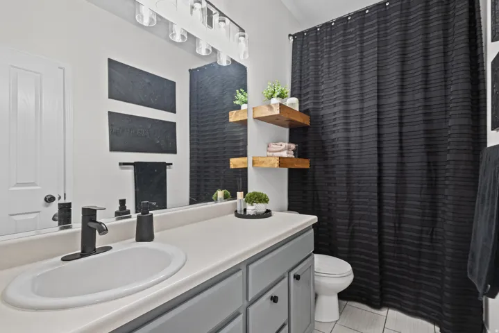 Guest bathroom featuring a single vanity with a white countertop, a black matte faucet, and gray cabinetry