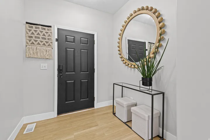 Entryway featuring light wood-finish flooring, a dark paneled door, and neutral wall tones.
