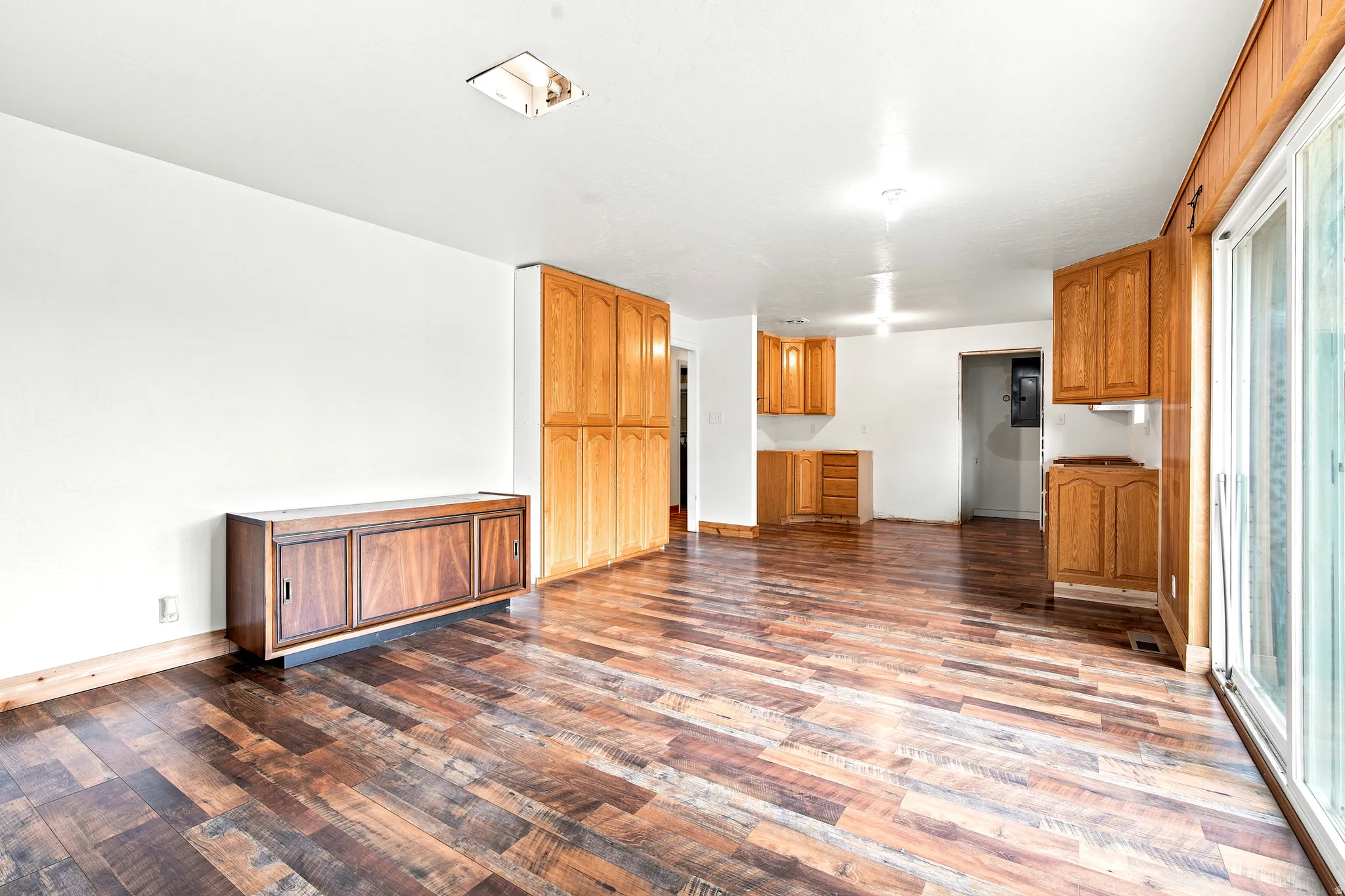 Expansive room featuring wood-finish flooring, white walls, and a built-in wood cabinet