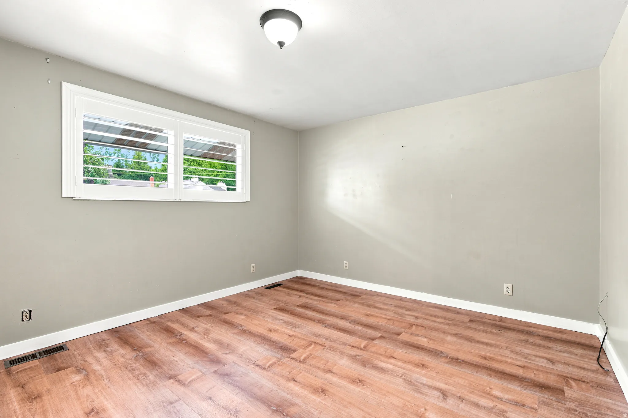 Room featuring wood-finish flooring, neutral wall tones, and white baseboards