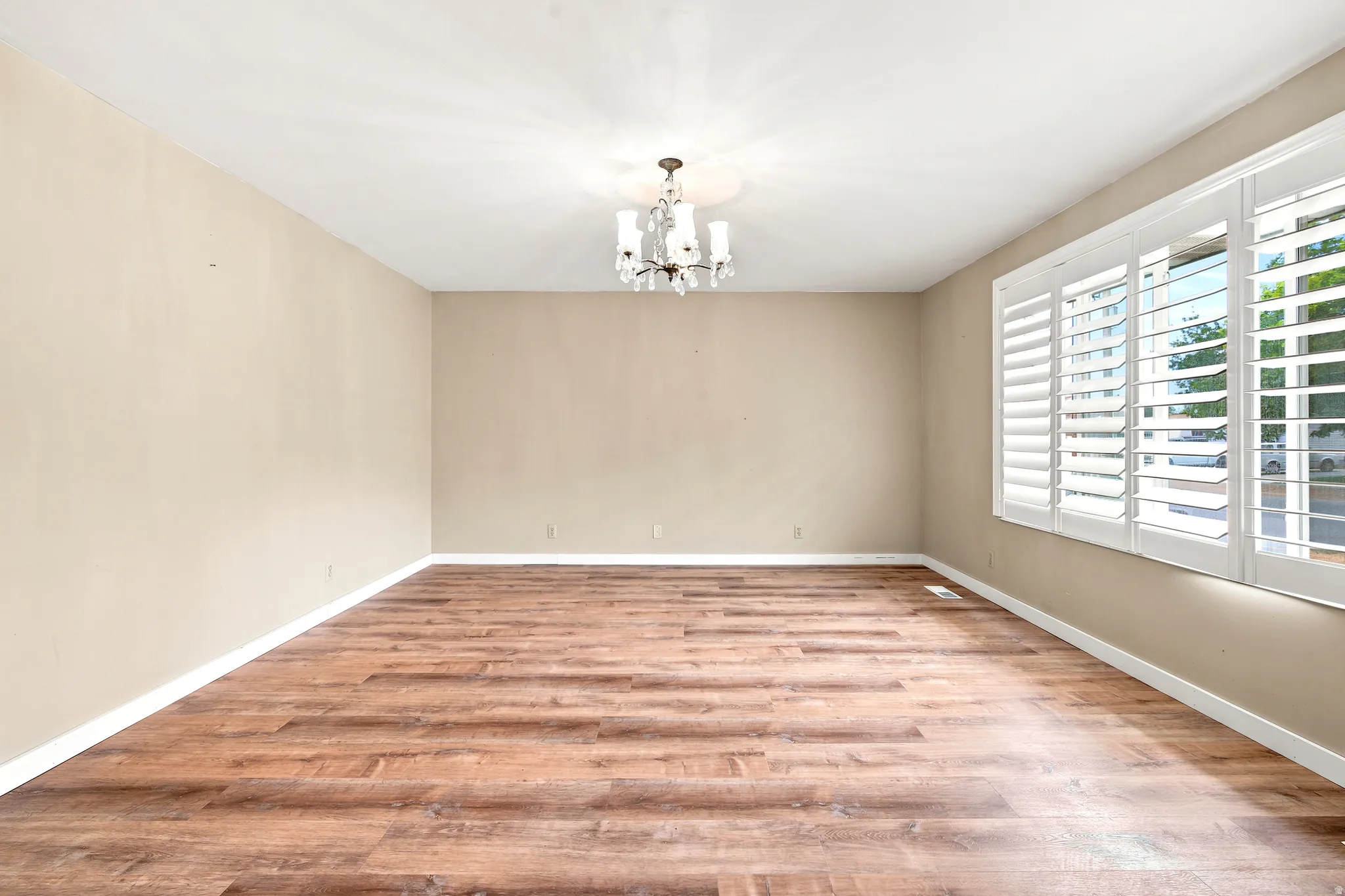 Spacious room featuring wood-finish flooring, neutral-toned walls, and white baseboards
