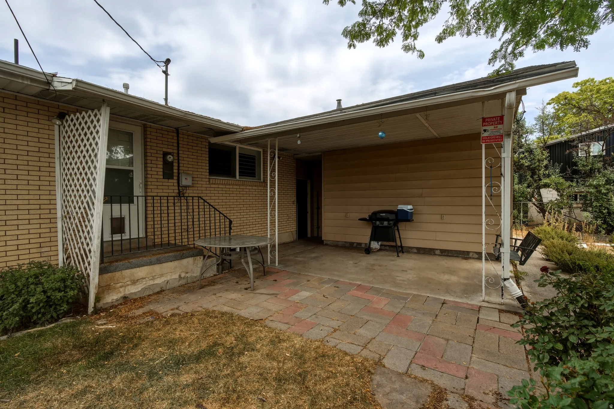 Covered patio area featuring a concrete slab and a multi-toned paver pathway