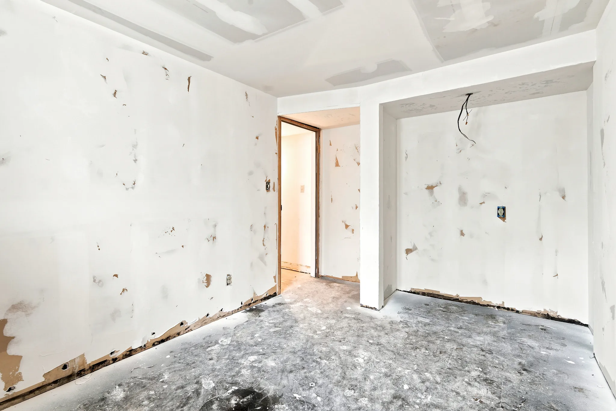 Unfinished interior space with exposed wallboard and concrete flooring