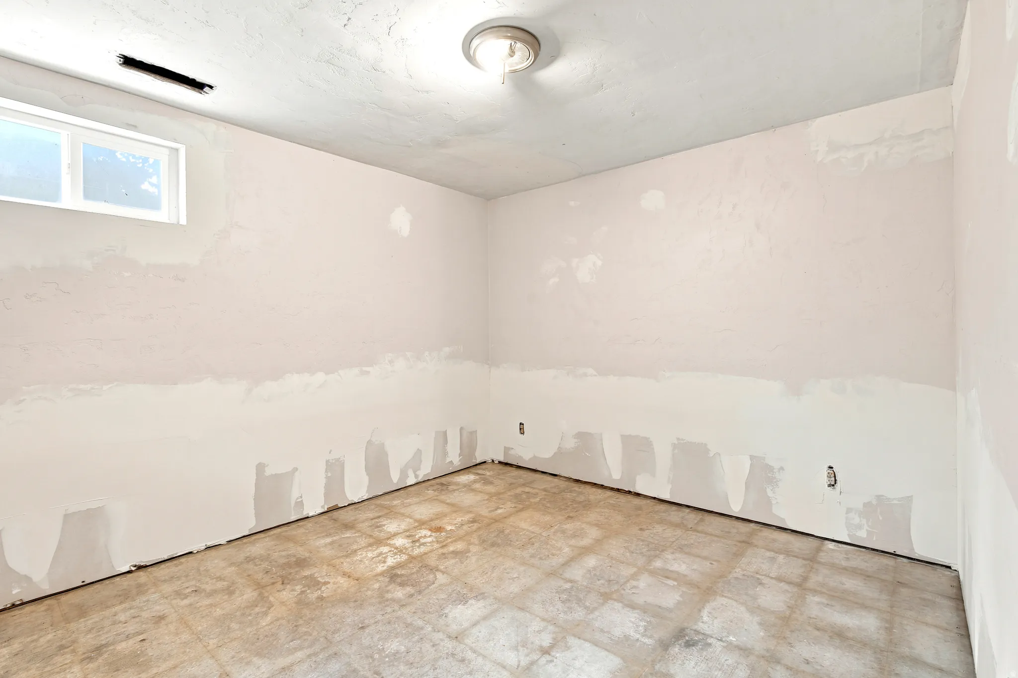 Room featuring a ceiling-mounted light fixture, recessed window, and walls prepared for finishing