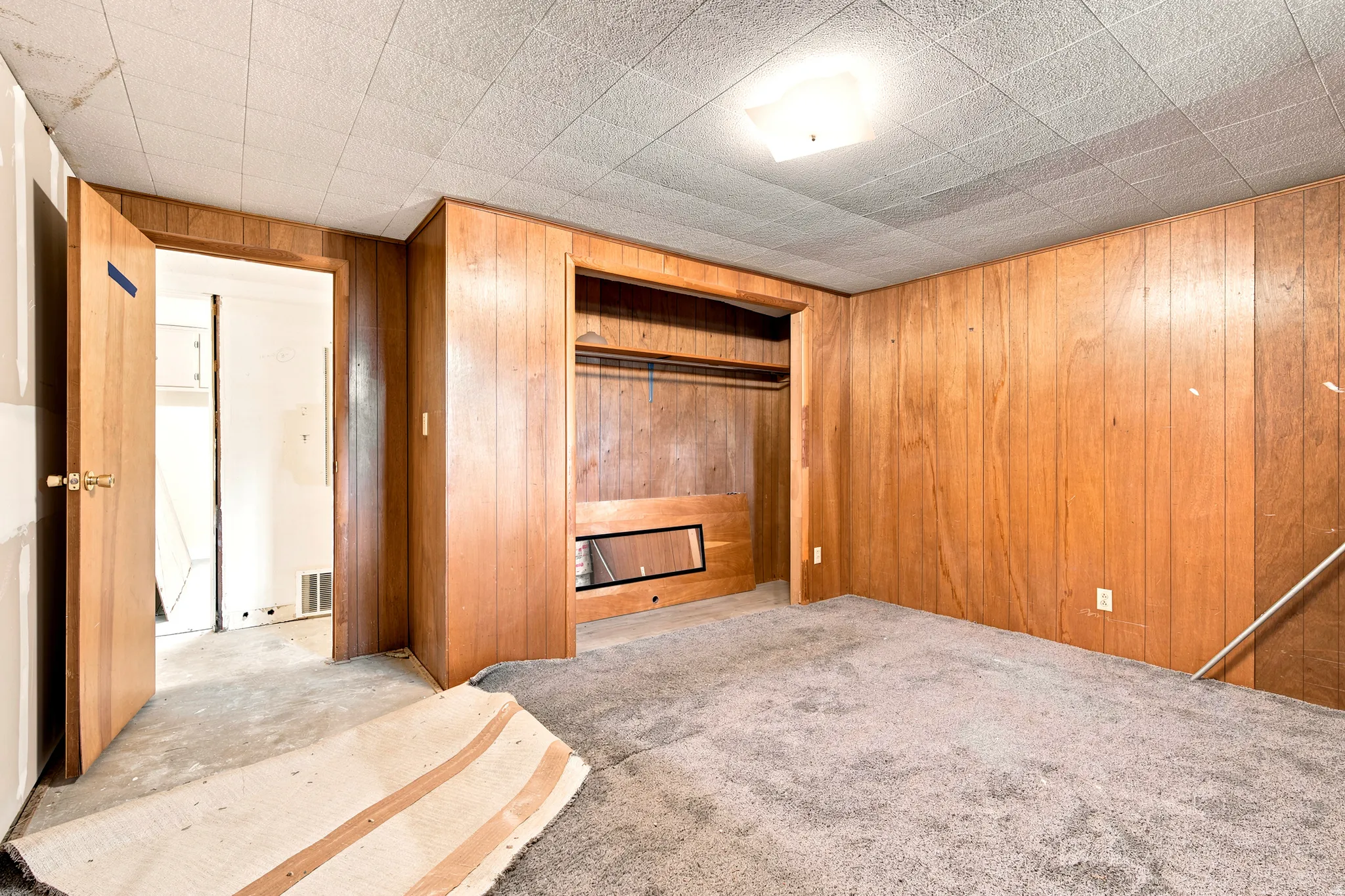 Room featuring wood panel walls, textured ceiling, flush mount lighting, and carpet flooring