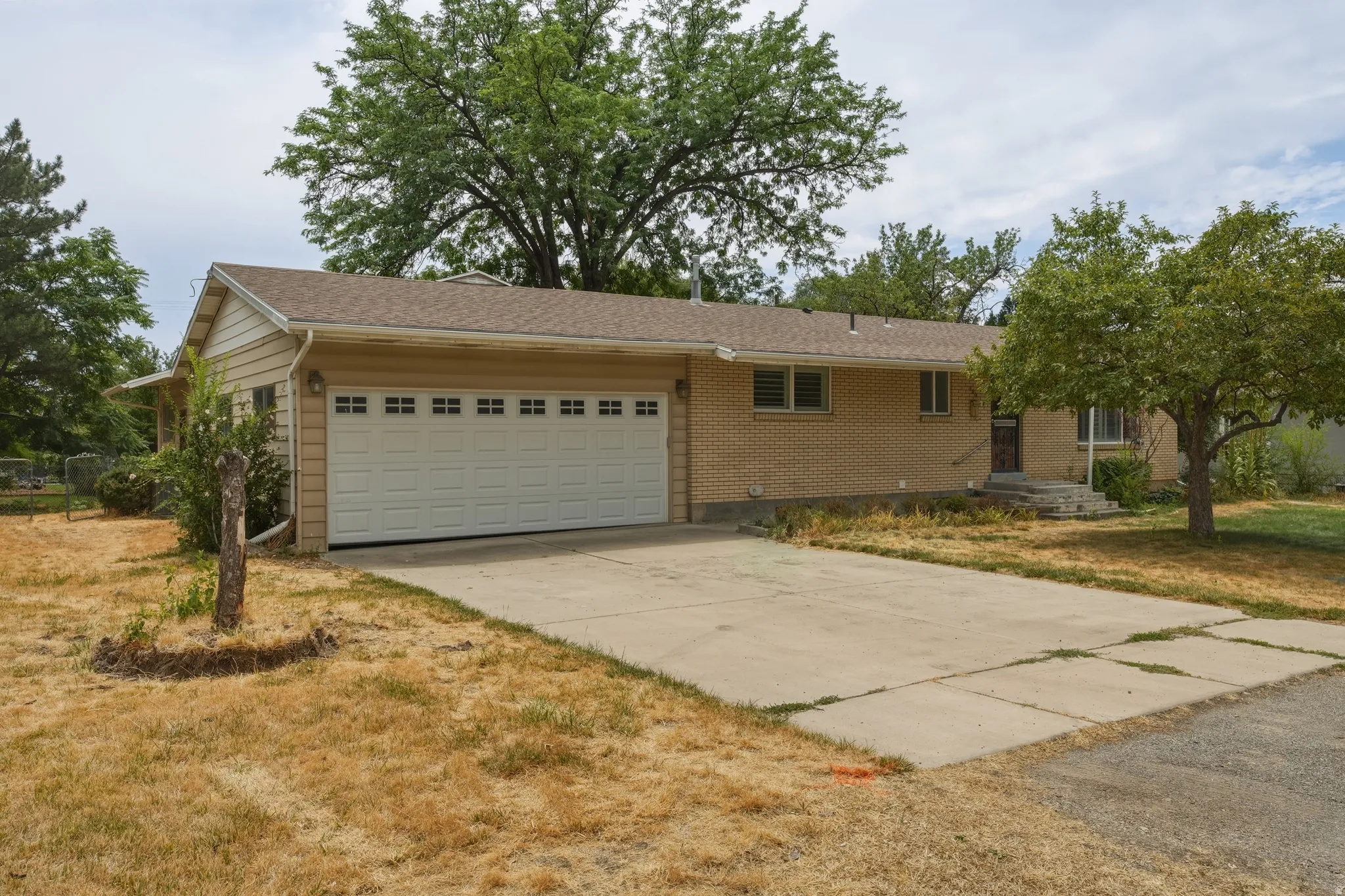 Ranch-style residence featuring a two-car garage with a panel door, a concrete driveway, and a combination of brick and siding exterior