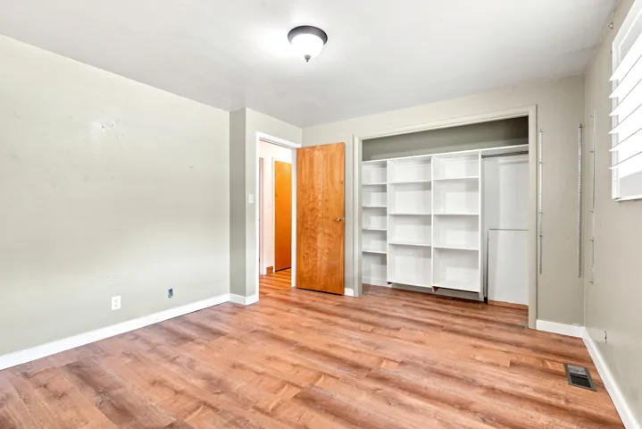 Room with wood-finish flooring, light neutral wall paint, and white baseboards