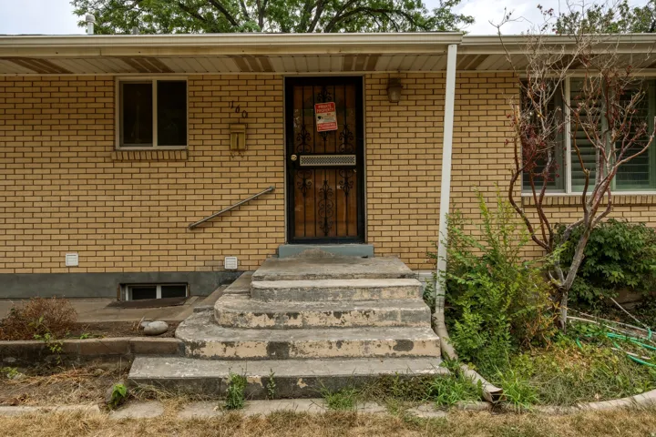 Brick facade exterior featuring a security screen door, concrete entry steps, and a handrail