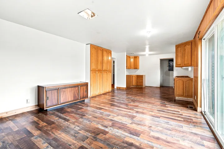 Expansive room featuring wood-finish flooring, white walls, and a built-in wood cabinet