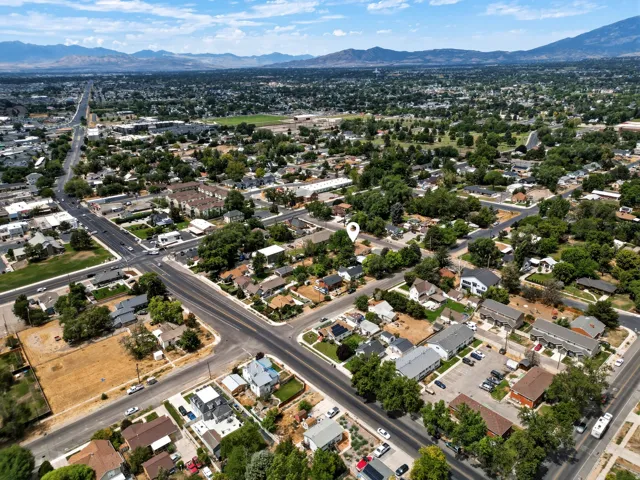 Aerial perspective of a developed urban area featuring residential properties, commercial establishments, and mature tree-lined streets