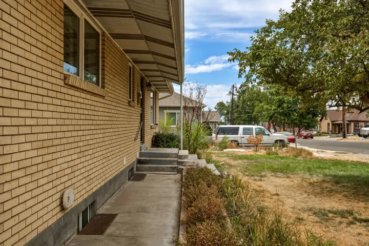 Brick exterior featuring a covered entry, concrete walkway, multiple windows, and partial landscaping