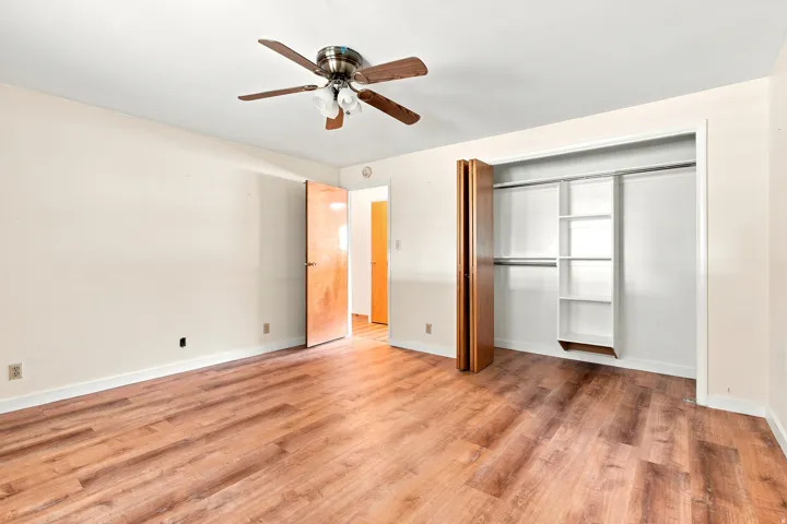 Expansive room featuring wood-finish flooring, a ceiling fan with integrated lighting, and neutral wall tones