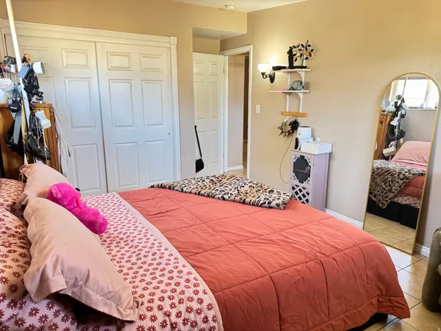 Bedroom featuring a sliding closet door with panel detailing, neutral wall color, and a wall-mounted light fixture