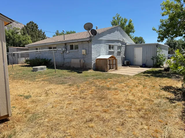 The property features a concrete block exterior with multiple windows, a flat-roofed attached structure with a white door, and a paved patio area
