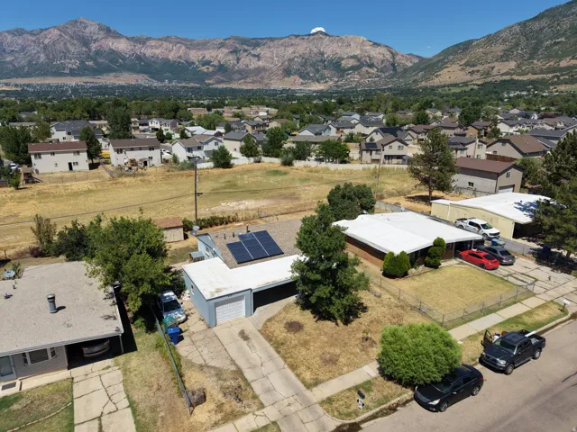 Property featuring solar panels, a two-car garage, and mature trees on a residential lot
