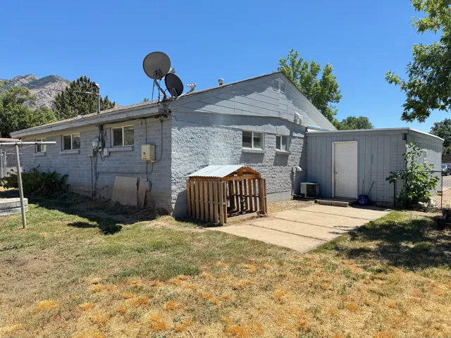 Rear exterior of a single-story residence featuring a concrete block construction and an attached storage structure with a white door