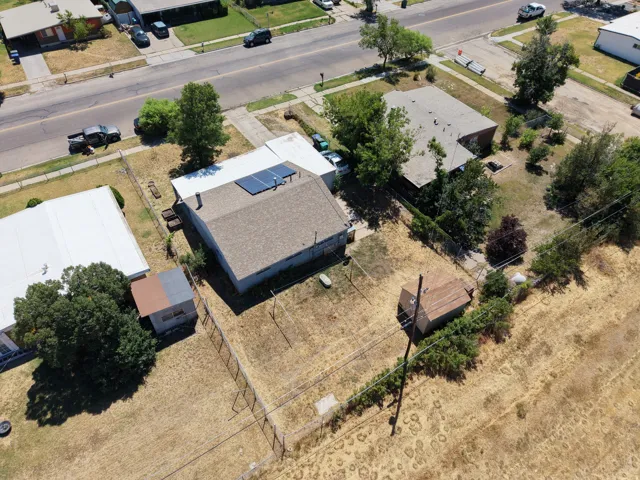 Property featuring a shingle roof, solar panels, and a fenced yard with mature trees