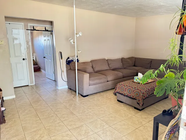 Neutral-toned tile flooring extends throughout this living space, featuring light beige walls and white baseboards