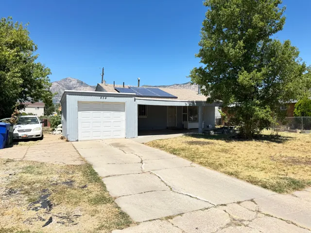 Detached garage with a paneled door, concrete driveway, and a residential structure featuring a covered porch
