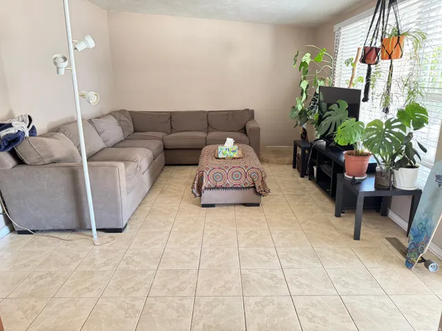 Spacious room featuring neutral-toned tile flooring, light wall paint, and a large window with horizontal blinds