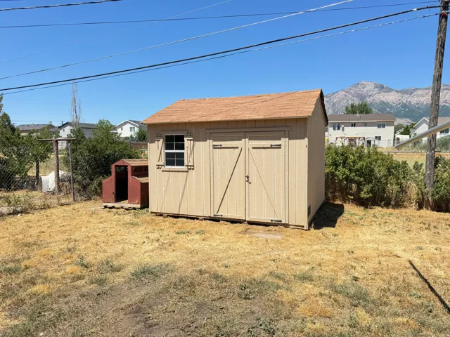 Detached storage shed with a shingle roof, double doors, and a side window